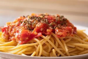 Spaghetti al pomodoro con basilico fresco, presentati in un piatto elegante.