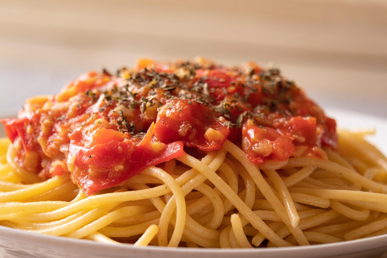 Spaghetti al pomodoro con basilico fresco, presentati in un piatto elegante.