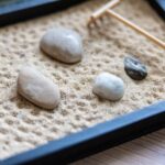 Giardino zen in un vassoio con sabbia, sassi e rastrello, simbolo di tranquillità e meditazione.